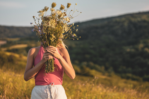 Woman holding bouquet of flowers and enjoys in the nature.