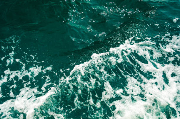 istock Dark turquoise sea water with white foam texture on the surface. Background image. 1266786607