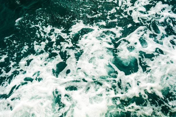 istock Dark turquoise sea water with white foam texture on the surface. Background image. 1266787154