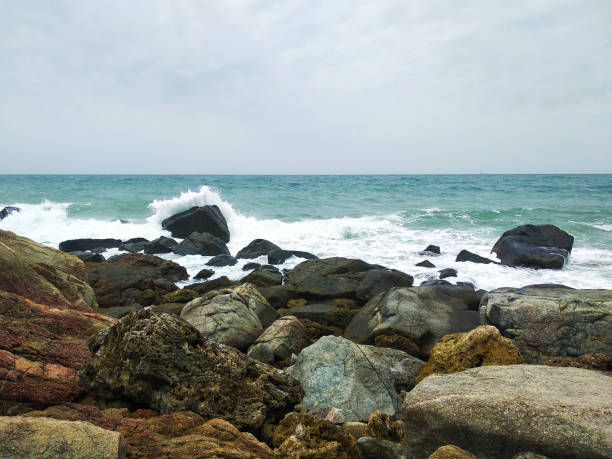 white waves hit the rocks on the sea shore in cloudy day