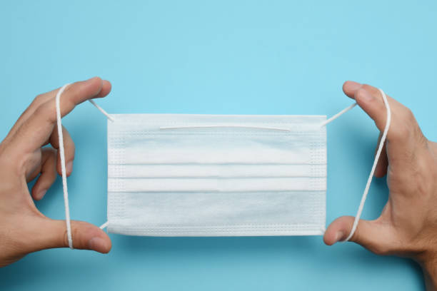 istock Man hands holding protective face mask, medical mask 1266795313