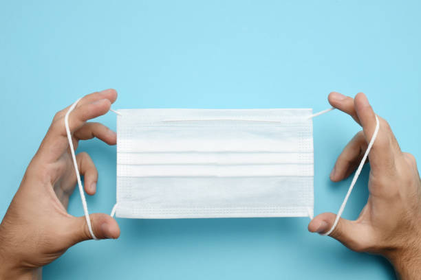 istock Man hands holding protective face mask, medical mask 1266797476