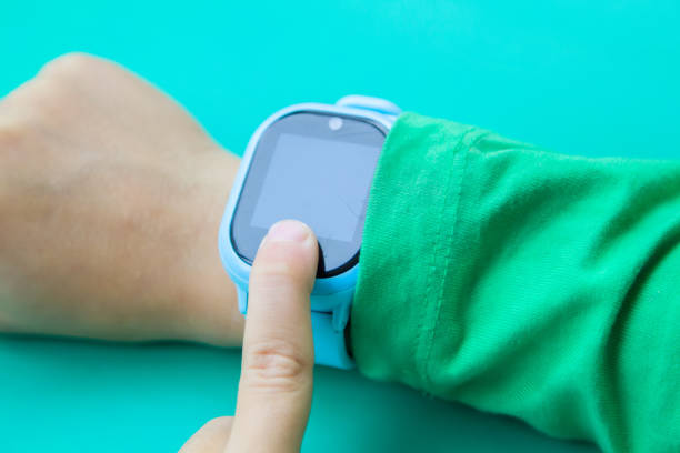 istock boy wants to call his parents on digital clock touching screen with his index finger. Modern children technologies. GPS tracker for kids, child tracking and parental control concept. 1266797821