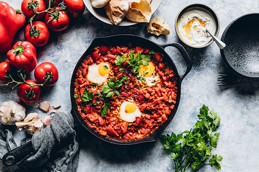 Top view of delicious shakshuka with eggs poached in a spicy sauce of tomatoes and vegetables. Vegetarian middle eastern food.