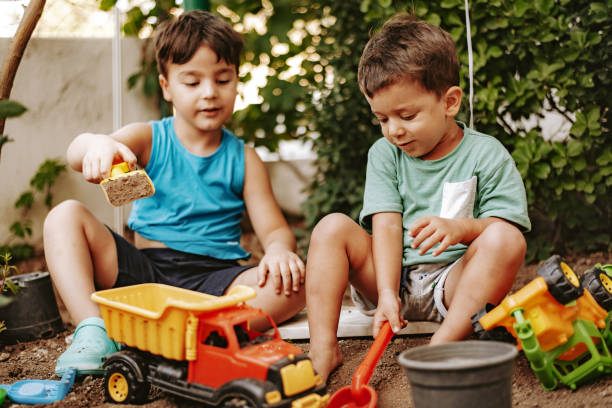 dos niños lindos jugando en el jardín - outdoor toy fotografías e imágenes de stock