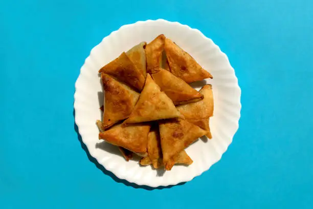 Photo of Triangular arabic chicken samosa on bright blue background