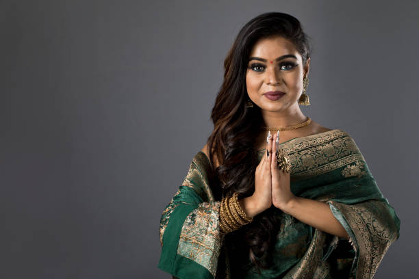 The bride gracefully, looking directly at the camera while proudly displaying her green bangles during her pre-wedding rituals. Her hands, decorated with intricate mehndi, highlight the beauty of the traditional jewelry.