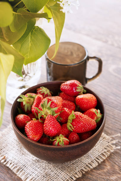 istock Glass ceramic bowl with ripe fresh strawberries and dark glass on a dinner table. 1266803093