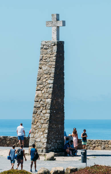 туристы рядом с крестом в кабо-да-рока, португалия маркировки самой западной точки в континентальной европе - cabo da roca стоковые фото и изображения