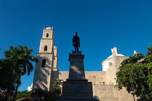 Hidalgo park with statue and doves with view on church 'El Jesus' in Merida with cloudless blue sky, Yucatan, Mexico