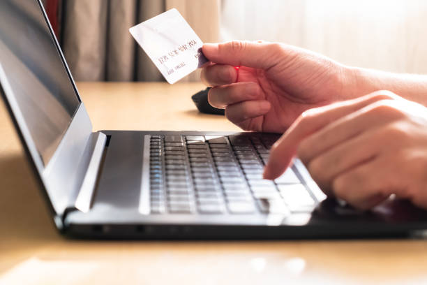 istock Selective focus at men hand holding credit card mock up while type payment information on laptop for online purchase from home during Coronavirus pandemic. Technology and Social distance concept. 1266807437