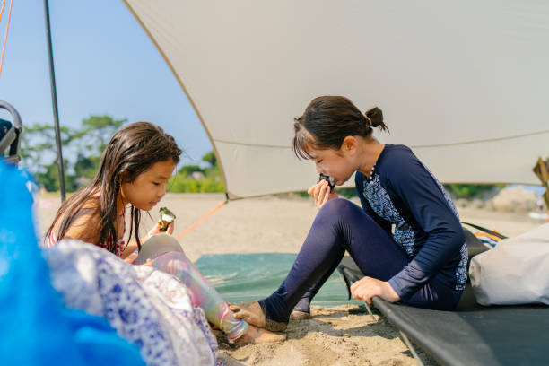 istock Sisters sitting at beach and eating lunch together 1266808529