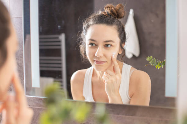 istock Young woman applying cream on her face 1266808539