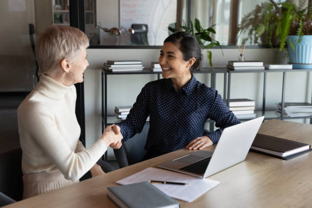 istock Happy two young mixed race business women shaking hands. 1266809648