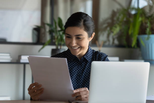 istock Happy young indian ethnicity female editor reading article on paper. 1266809676