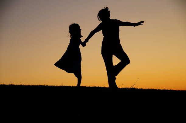 istock Mother and daughter dancing at dusk 1266809891