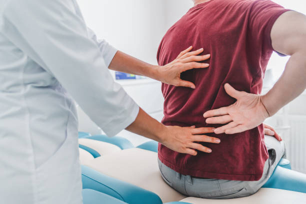 cropped close up of female orthopedist examining patient's back in clinic - human vertebra fotos imagens e fotografias de stock