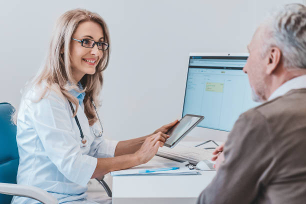 istock Friendly doctor talking with elderly man patient in the office using digital tablet 1266812080