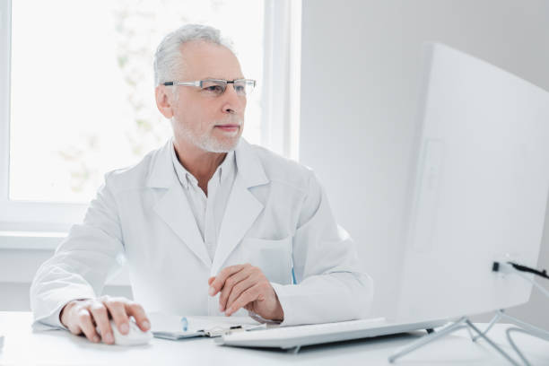 istock Senior male doctor in office using desktop computer 1266812141