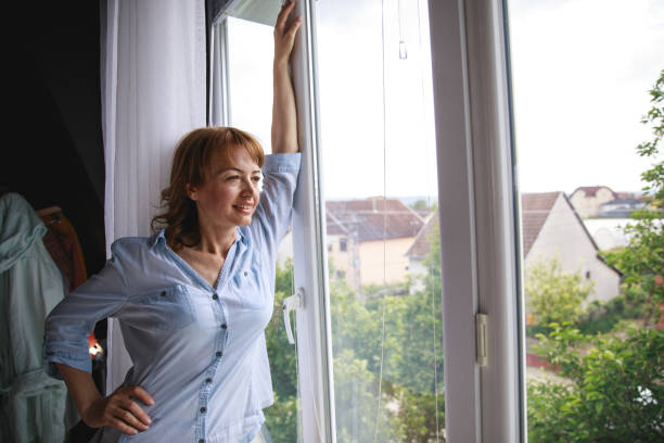 istock Enjoying the big windows of her apartment 1266813263