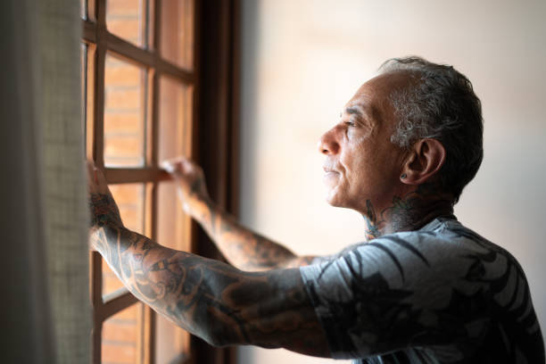 istock Mature man contemplating, looking through the window 1266813849