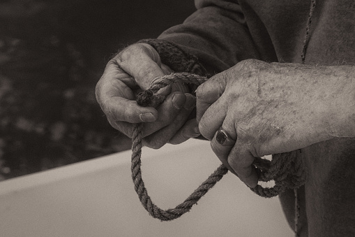 Senior Male Hands Tying Rope on a Boat - Black and White