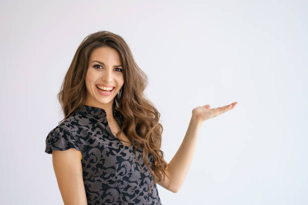 istock A young beautiful woman smiles on a white background and points to the side. Copy space 1266814894
