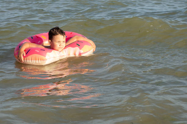 istock A 5-year-old boy bathes in a donut-shaped life ring on a sunny day. 1266817619