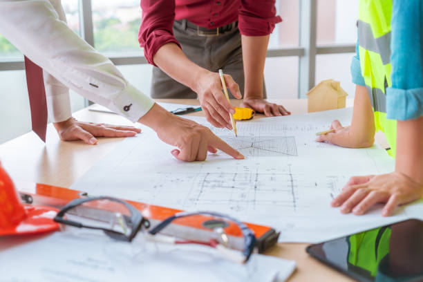 istock Construction team with business man engineer and architect is poiting on working table with building plan 1266817676