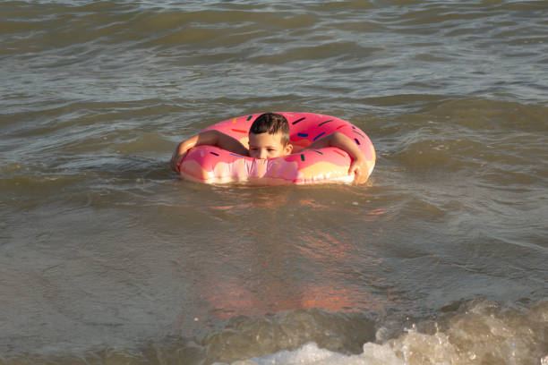 istock A 5-year-old boy bathes in a donut-shaped life ring on a sunny day. 1266817698