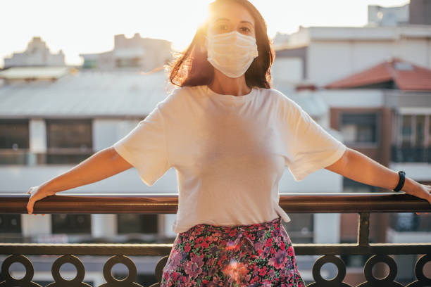 istock Woman wearing face mask on balcony during lockdown 1266818869