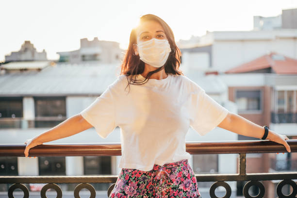 istock Woman wearing face mask on balcony during lockdown 1266818895