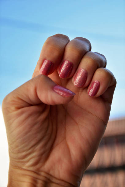 istock Hand with pink painted nails with glitter 1266821535