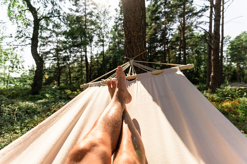 Personal perspective of a man lying in a hammock in the sun, inside a beautiful Swedish forest.