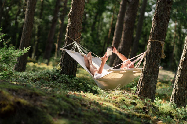 istock Man in a hammock reading a book on a tablet 1266821573