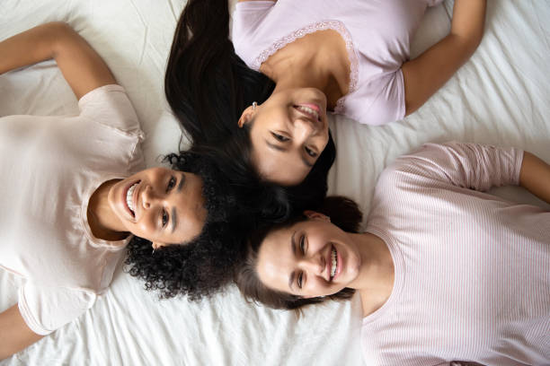 istock Three diverse best girlfriends smiling lying in bed top view 1266822030