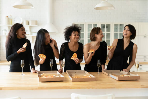 istock Five gorgeous women in elegant dresses drinking champagne eating pizza 1266822071