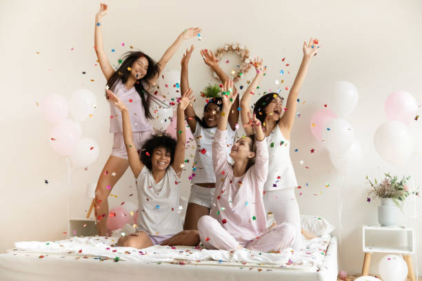 istock Happy multiethnic girls catching playing with falling multi colored confetti 1266822074