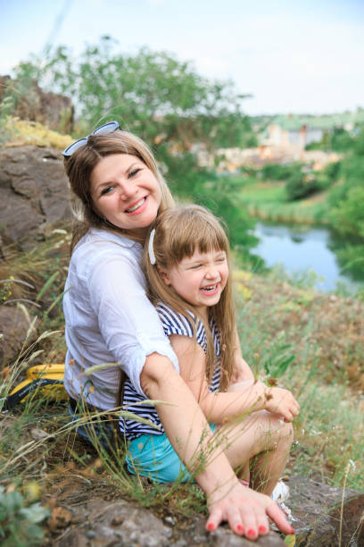 istock Joyful mom and daughter sit on a stone in the open air 1266823140