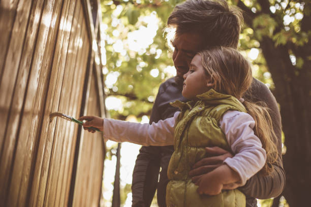 istock Now, it is her turn to paint the gate while father supervises 1266823515