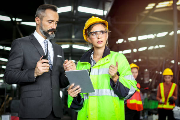 istock Young beautiful woman industrial engineer worker wearing safely helmet and protective clothing, holding digital tablet discussing with businessman boss at manufacturing industry 1266824253