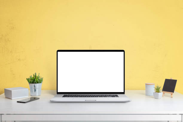 istock Laptop computer mockup on office desk with yellow wall in background. Isolated screen in white for web site design promotion 1266827568
