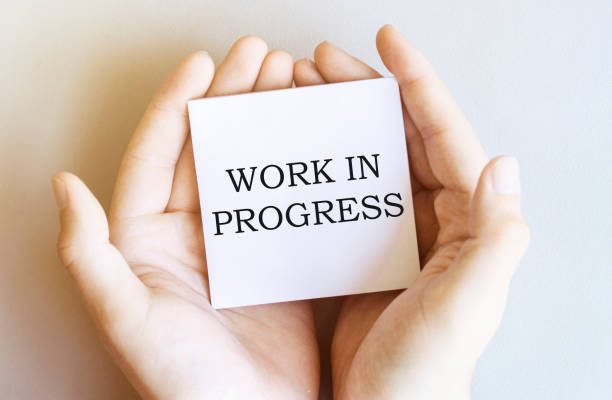istock white paper with text Work In Progress in male hands on a white background 1266828825