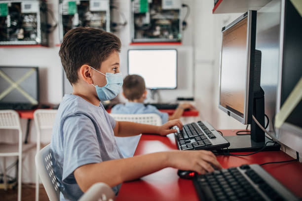 colegial usando máscara protectora en el aula de computación - computer lab child internet development fotografías e imágenes de stock