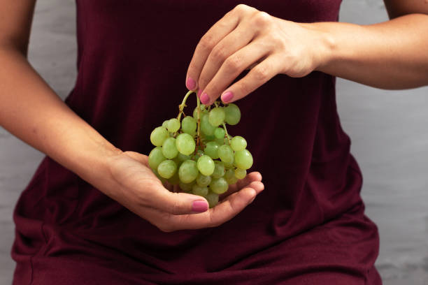 istock young woman holding bunch of grapes 1266832021