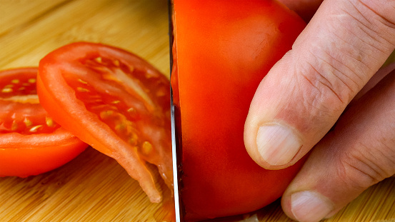 Chefs hands are cutting juicy ripe tomato with kitchen knife on wooden cutting board. Close-up. 16x9 format. Indoors.