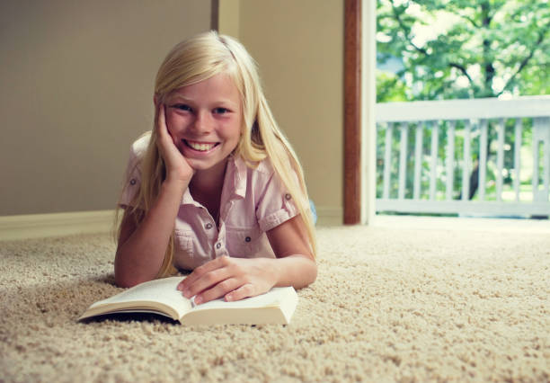 istock Girl lying on carpet, reading book 1266832154