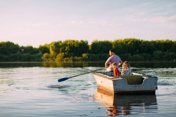 la giovane famiglia va in barca sul fiume o sul lago in estate. vista posteriore. fotografia per annuncio o blog su famiglia e viaggi - sailing nautical vessel family lake foto e immagini stock