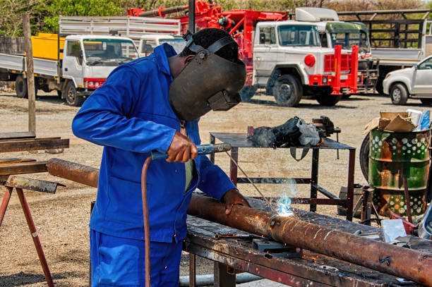 afrikanischer schweißer auf dem hof einer industrieanlage - welder manual worker african descent steel worker stock-fotos und bilder