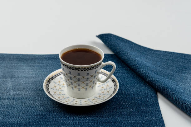 istock Cup of coffee on a jeans napkin on a white background 1266836117